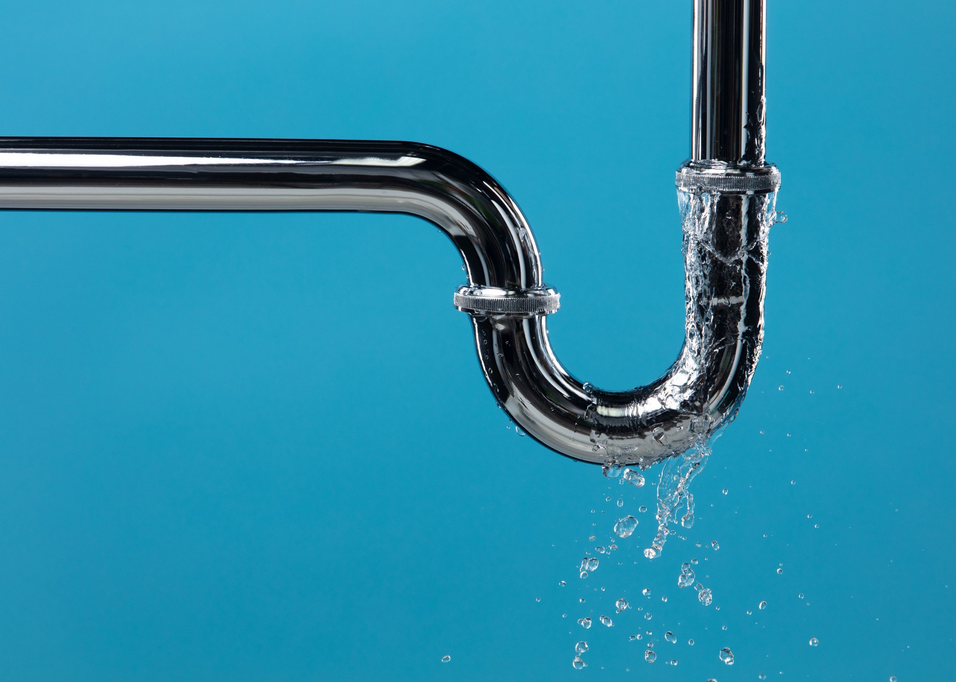 Leaking water from chromium stainless steel pipe under sink. Drain leak water from pipe plumbing in bathroom as water clogged drop. Blue bathroom background isolated