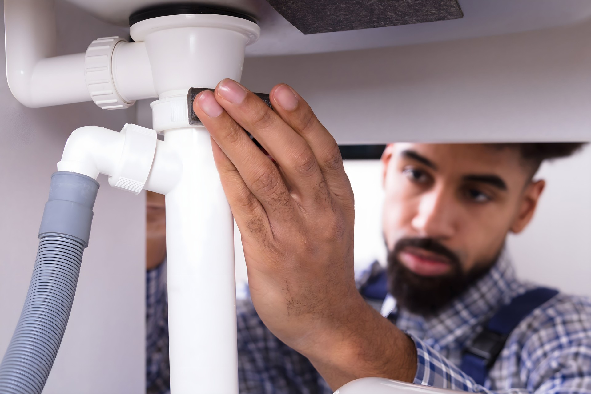 Close-up Of A Plumber Fixing Sink Pipe