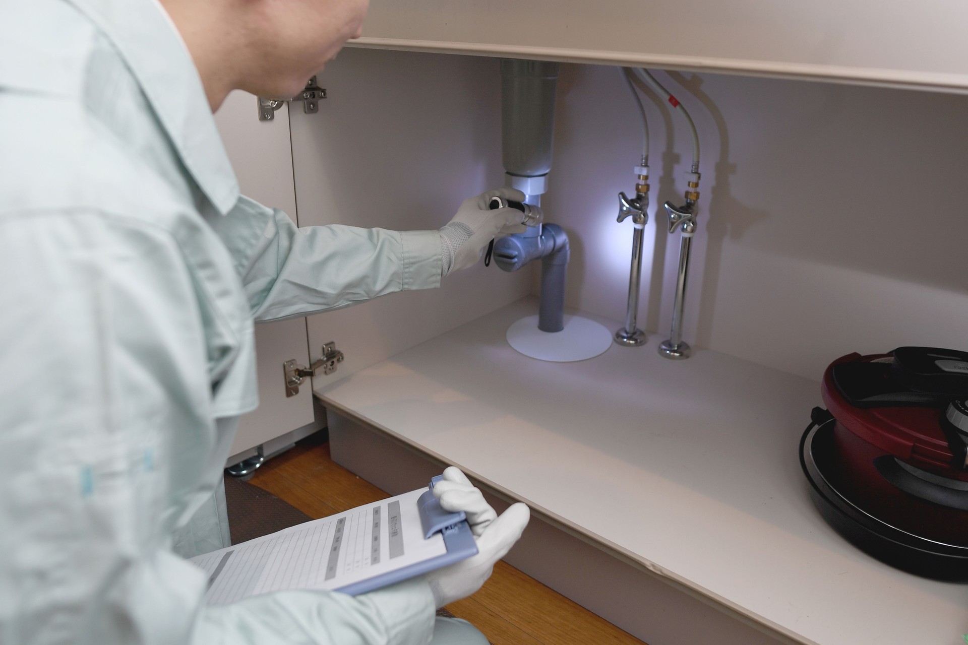 Asian man in work clothes checking under the sink